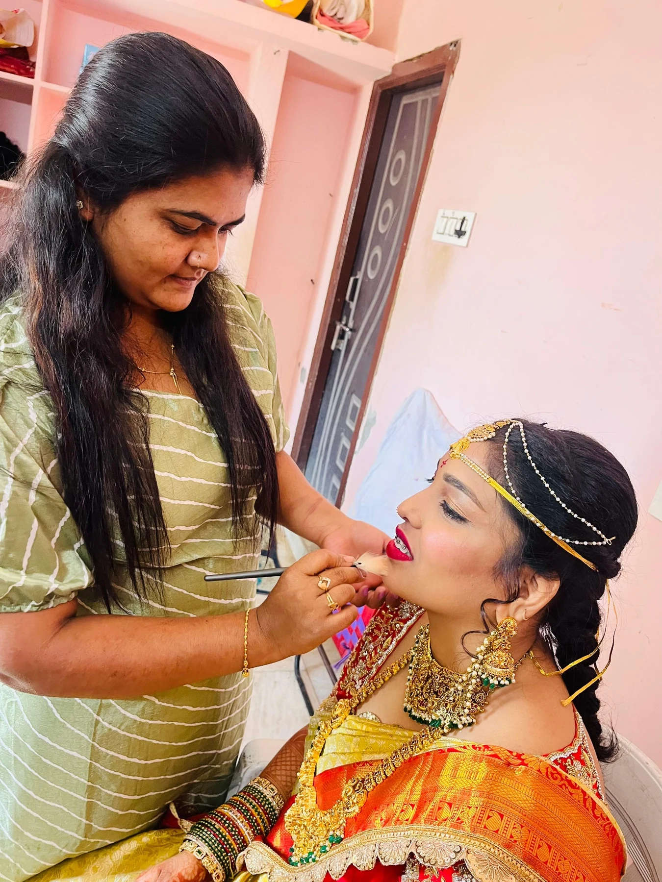 Bindu carefully applying makeup to a bride